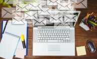 Un escritorio con un portátil y varios sobres de email