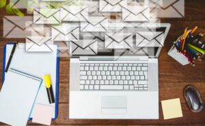 Un escritorio con un portátil y varios sobres de email